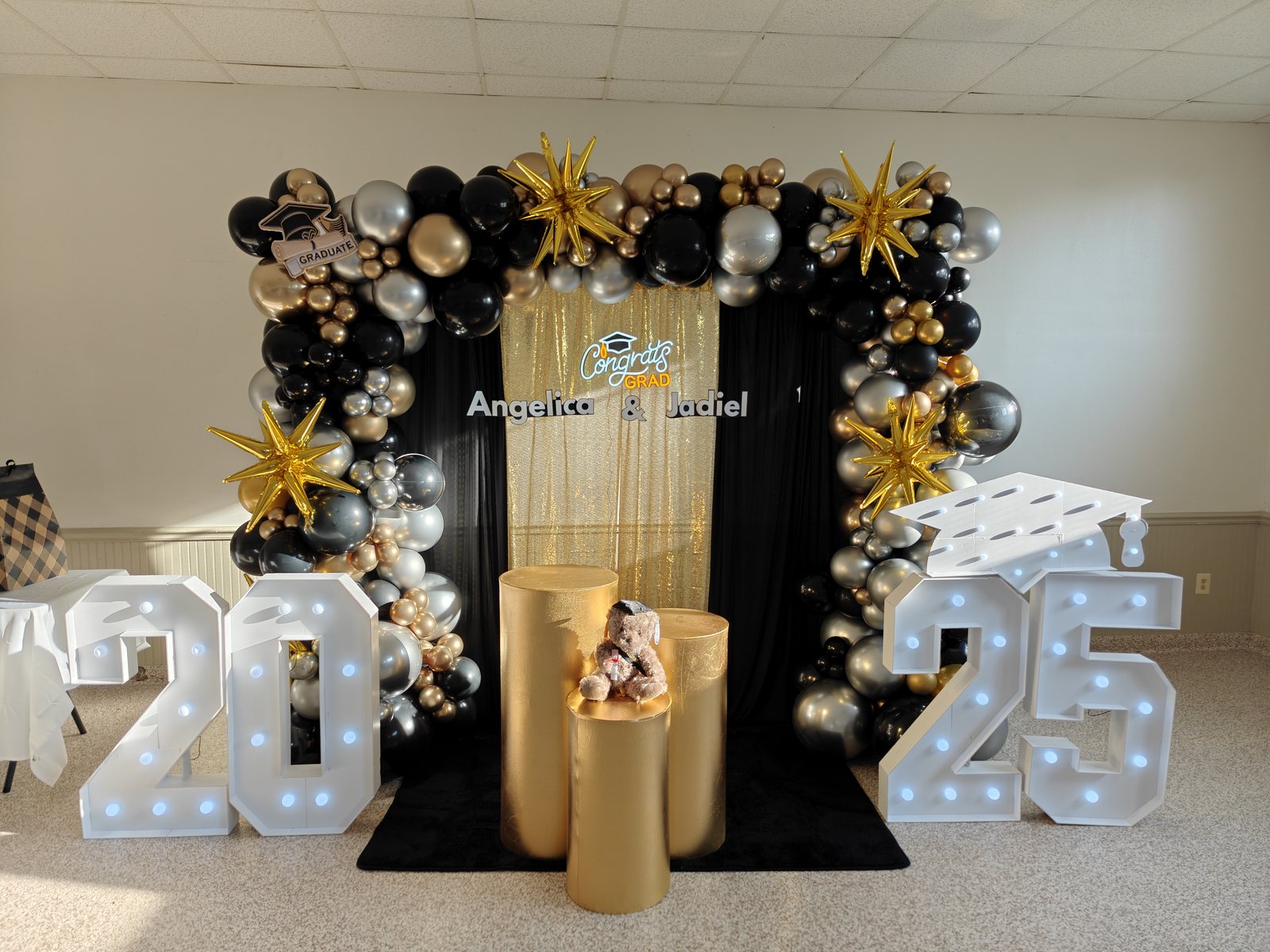 Black, gold, and silver graduation balloon installation with marquee numbers and custom signage